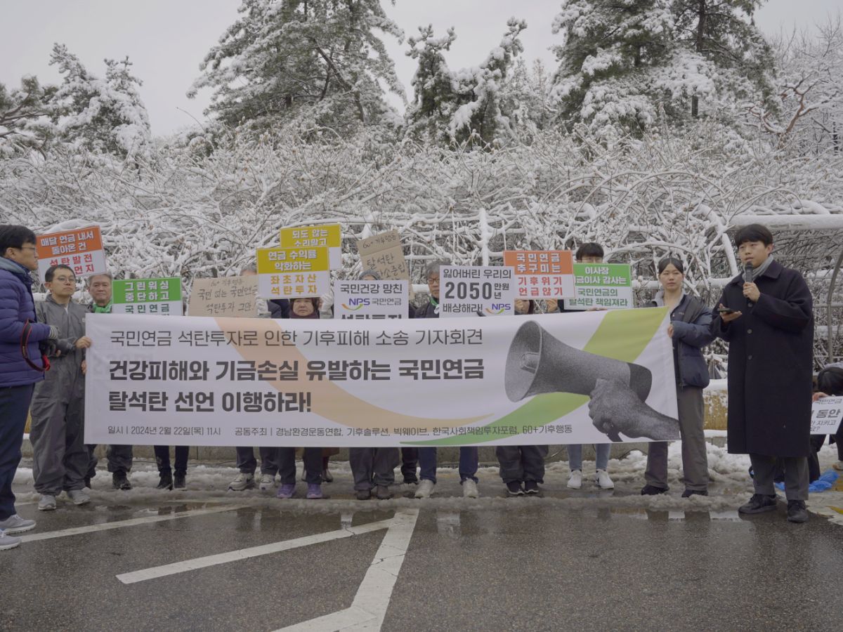 A photo of protestors holding up signs and banners in Korean calling on NPS to stop funding KEPCO's coal. There is snow in the background on the trees.