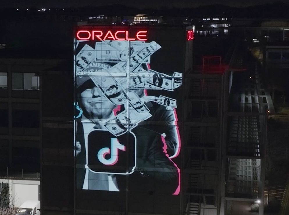 A projection of President Donald Trump with money floating on an Oracle building at night.