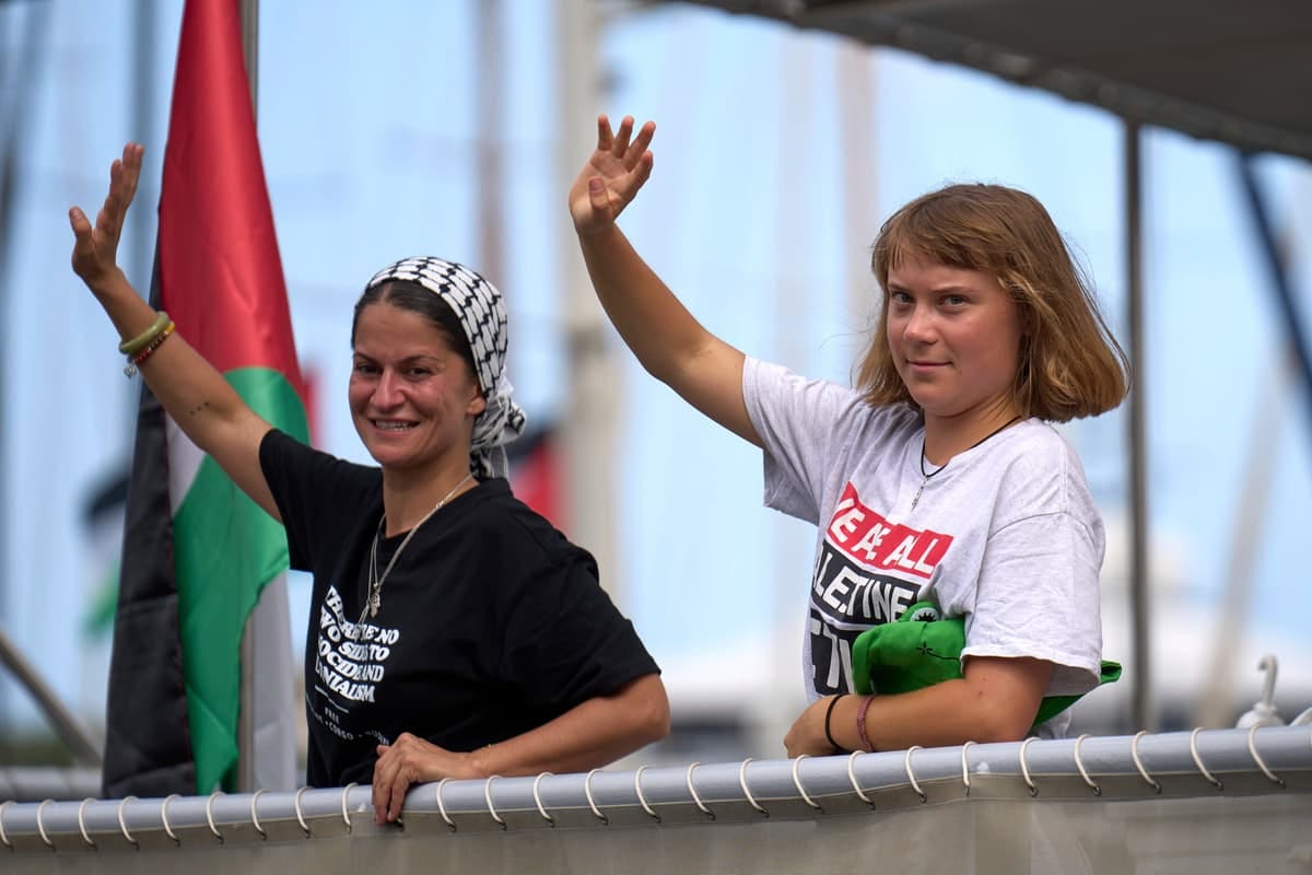 Greta Thunberg and another woman wave from aboard a ship as part of the Gaza flotilla