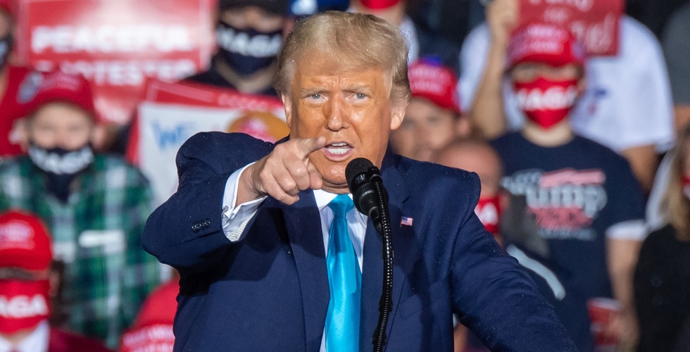 Close up of Donald Trump standing at a lectern and pointing into the crowd.