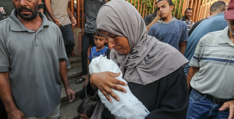 Funeral of a Palestinian child who died of starvation due to the Israeli blockade on the Gaza Strip and the lack of humanitarian aid in Khan Younis, southern Gaza Strip. A woman holds a small child wrapped in a shroud in her arms.